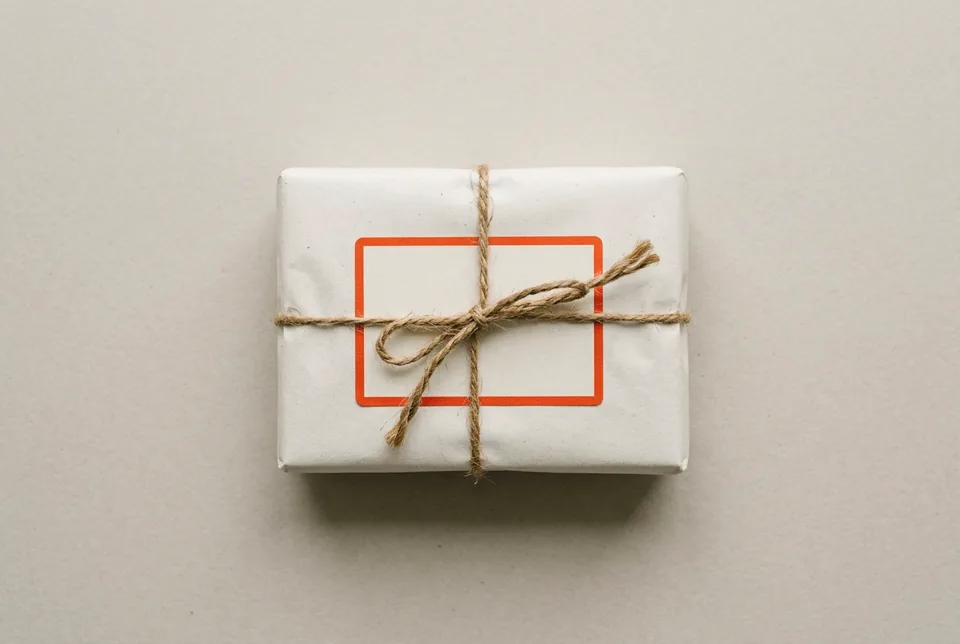 A paper-wrapped parcel tied with string, with a blank orange-red bordered label