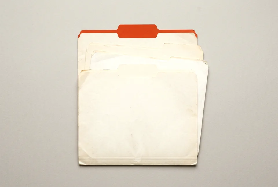 Four manila file folders fanned out, the top tab orange-red