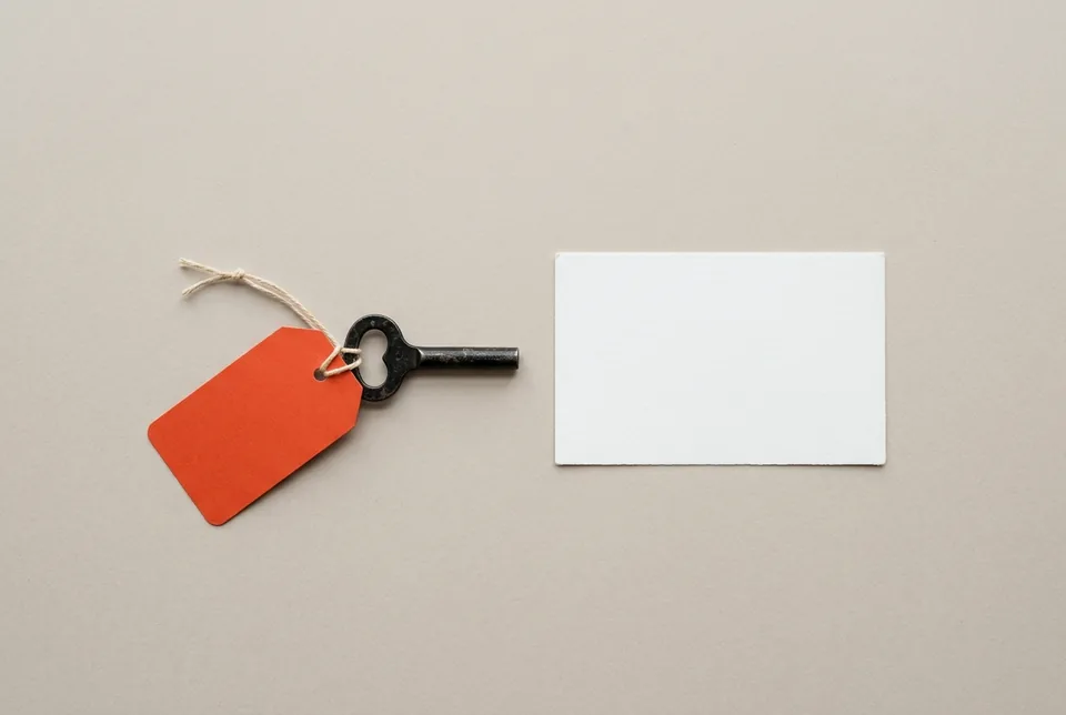 A black wind-up key with an orange-red tag, beside a blank index card