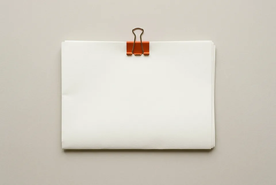 A blank three-page document held by an orange-red binder clip